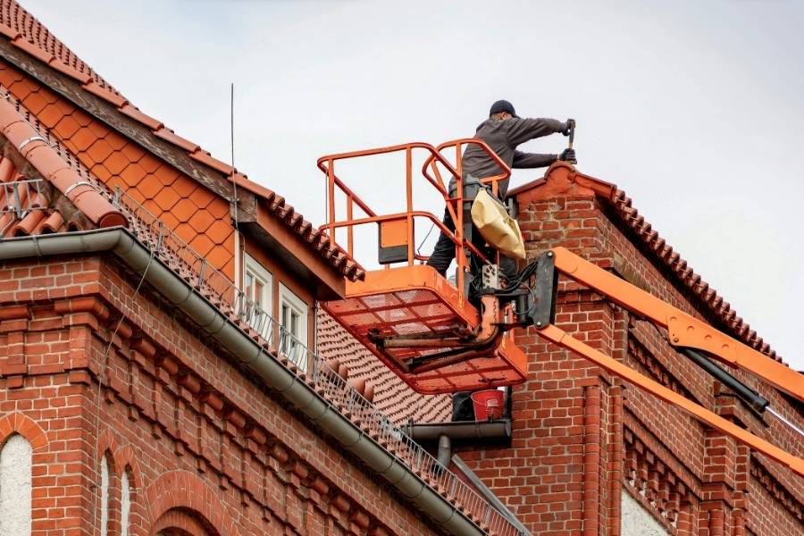 Roofer Performing Maintenance on Red Brick Building